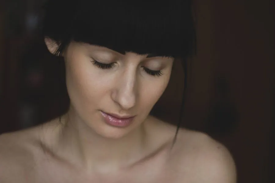 A woman with dark hair and a fringe looking down
