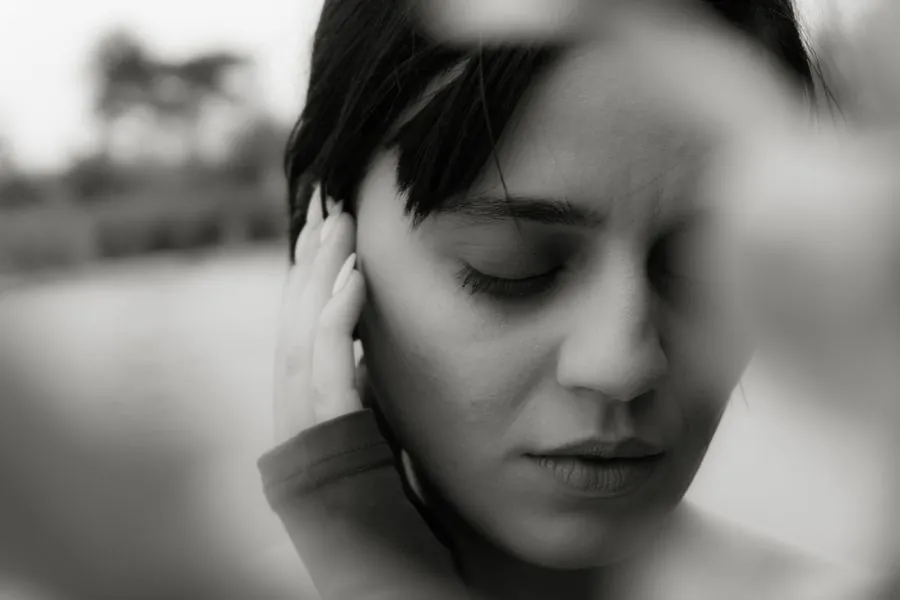 A woman with short dark hair, eyes closed, in monochrome