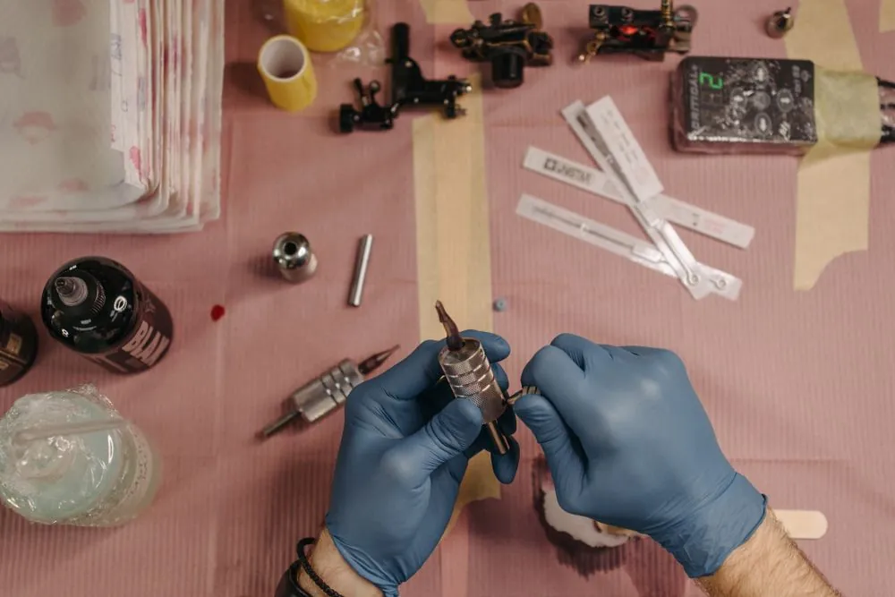 Tattoo tools and pigment cups on a pink cloth